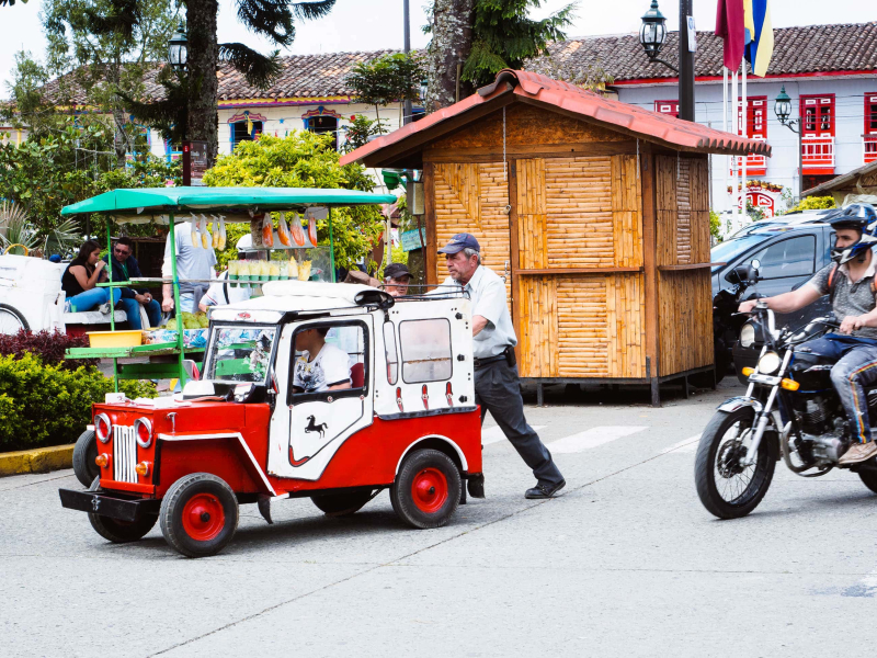 A kid gets pushed around the main plaza in a little wooden jeep