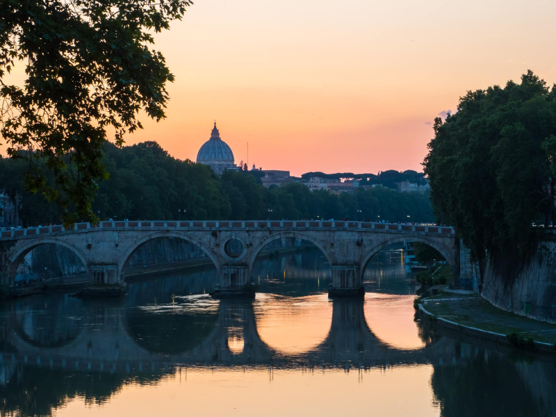 Sunset over the Ponte Sisto bridge and the dome of St. Peter's Basilica
