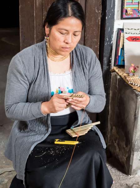 A woman at a workshop in Peguche cuts and binds bamboo stalks to make traditional pipes