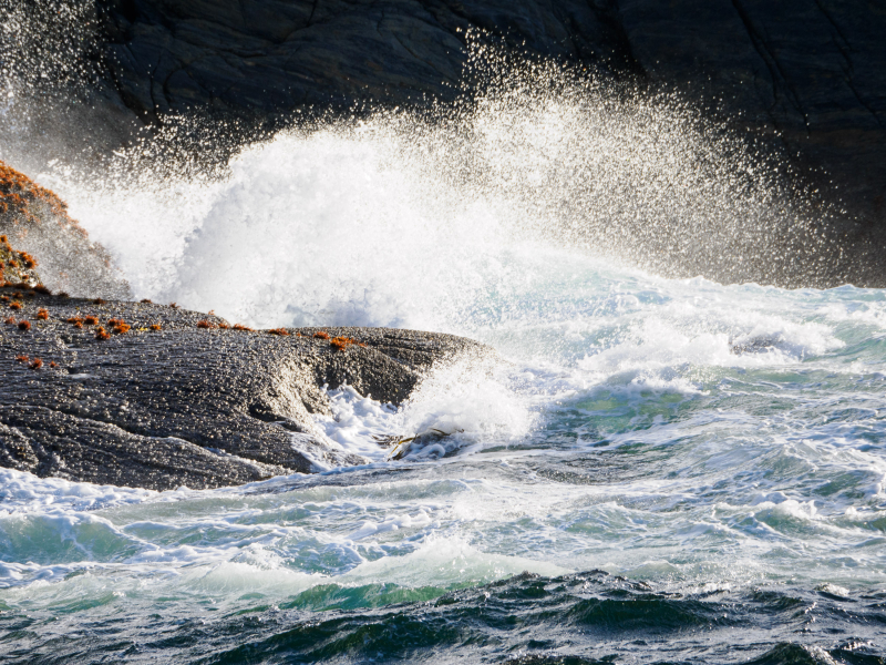 Waves crashing on rocks at the mouth of the fjord
