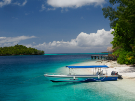 Bright blue water and a fancy dive  boat at the Meos Ambower homestay near Pam Island