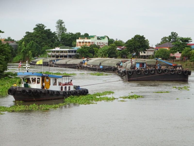 A tugboat pulling a row of barges. From the mid-1300s to the mid-1700s, Ayutthaya was a center of commerce and the most important city in Thailand.