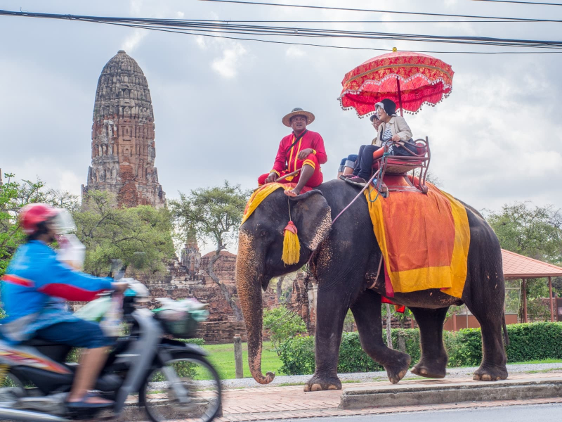 Tourists getting an elephant ride past one of Ayutthaya's 14th-century ruins