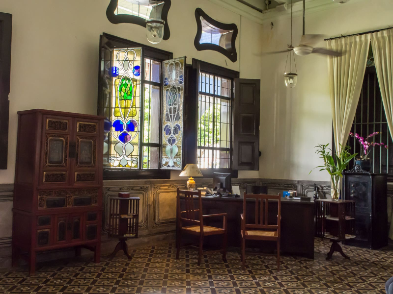 The entrance hall, for receiving guests, features English tile, Art Nouveau stained glass, and Chinese shophouse-style butterfly-shaped windows