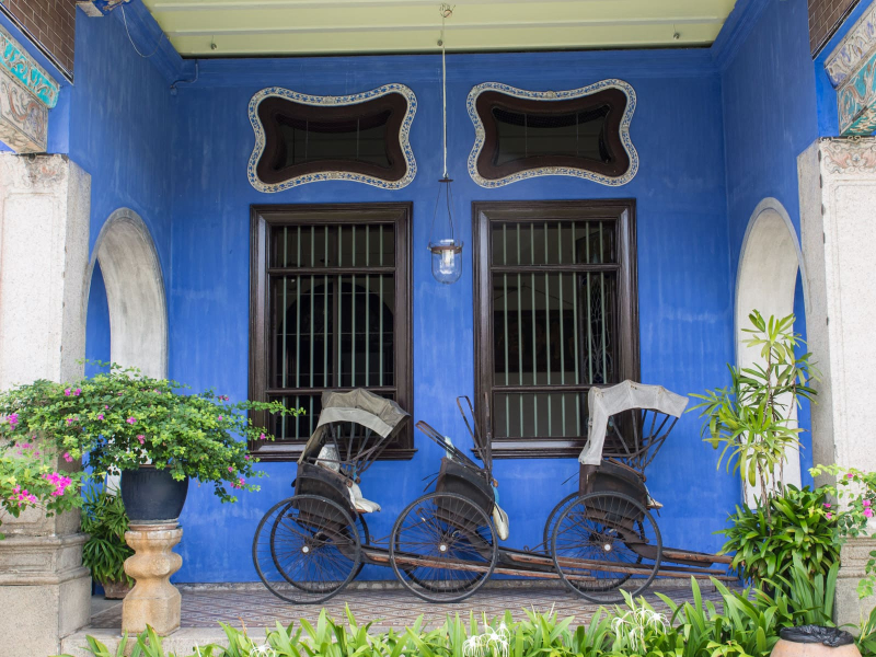 Old rickshaws displayed in front of the Blue Mansion