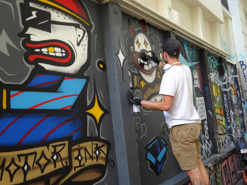 A graffiti artist at work in an alley