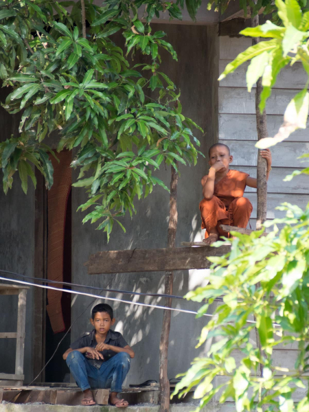 A young monk and a local boy relax in the midday heat (many poor families send young boys to a pagoda to be fed, housed, and educated)