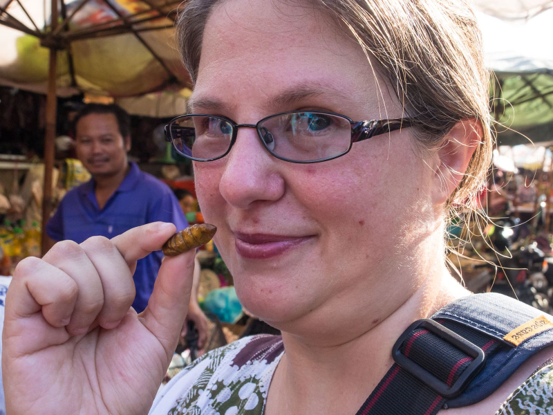 Melissa trying a fried silk worm larva (the outside went crunch but the inside was mushy and flavorless)