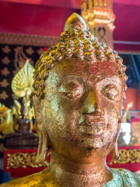 As an offering, worshipers sometimes buy small squares of gold leaf that they press onto Buddha statues, which gives the statues a mottled look