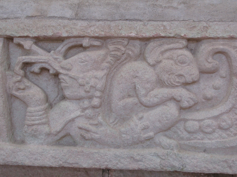 A carving of a man with some kind of rodent, maybe an agouti