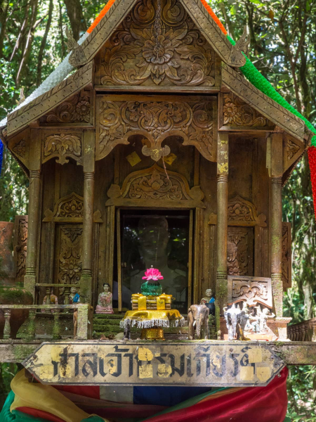 A shrine at the end of a mossy forest trail near the summit