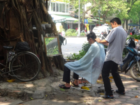 No need to sit in a stiflingly hot barbershop to get a haircut, when a chair and a tree will do
