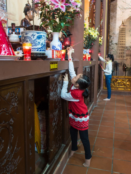 This little girl had to reach high to light her stick of incense