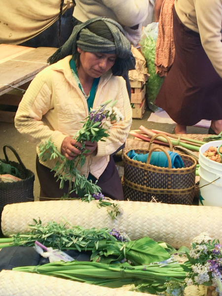 A seller of local herbs and flowers in a market