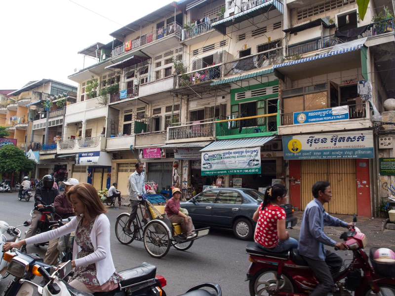 A typical street scene in Phnom Penh, with apartments built over shops and a traditional cyclo (pedal rickshaw)