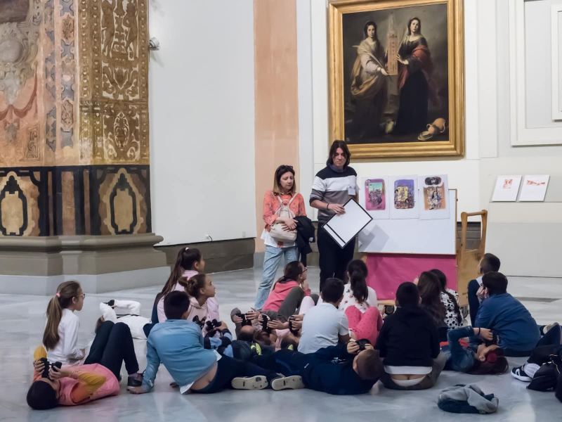 A school group sits in front of a painting of two Seville saints by local 17th-century artist Bartolomé Murillo