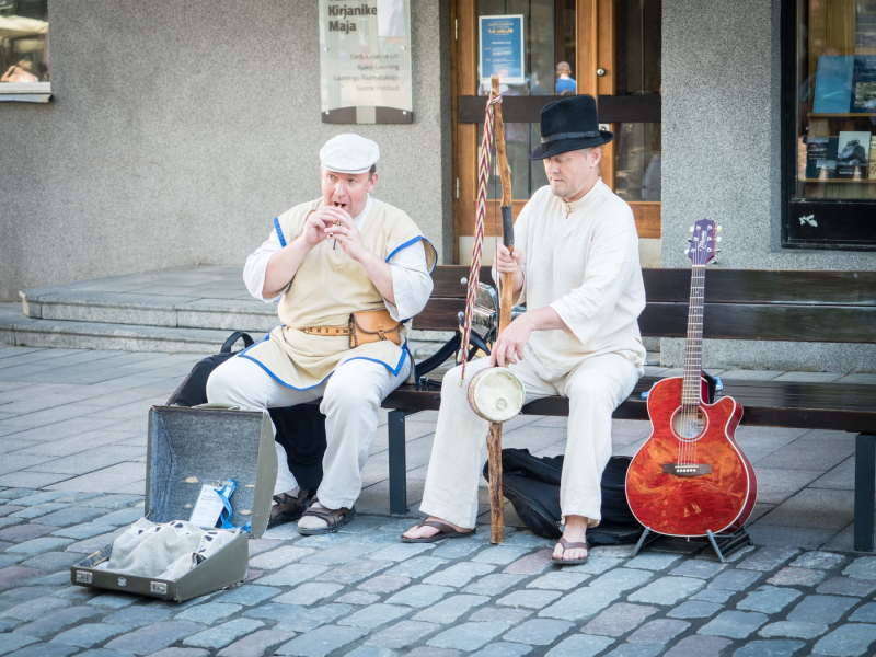 Folk musicians busking with a reed pipe and a bow with a string and a drum