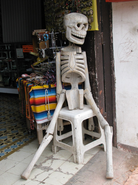 A wooden Day of the Dead skeleton outside a shop 