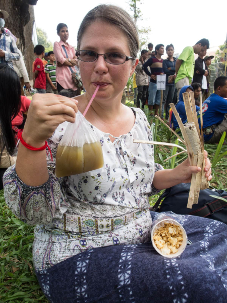 Melissa with her festival treats: a bag of sugar cane juice, sticky rice with black beans sold in a bamboo tube, and kettle corn