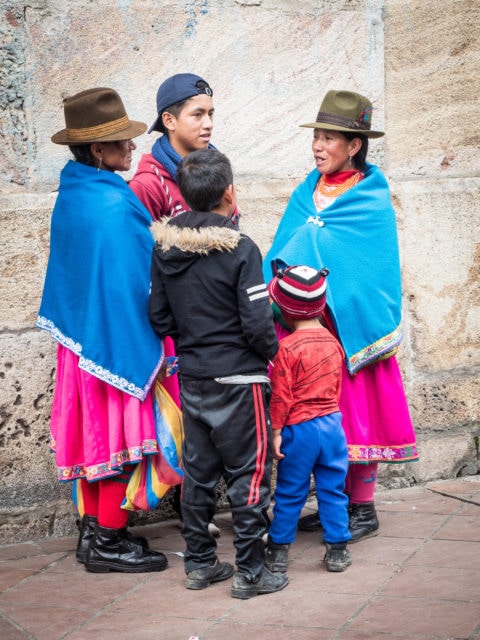 Indigenous family  in bright blue and pink talking outside the church