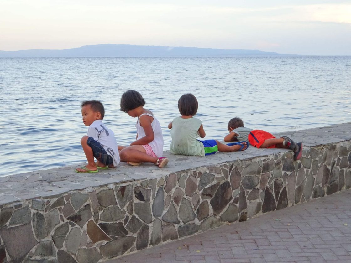 Children sitting on seawall in Dumaguete