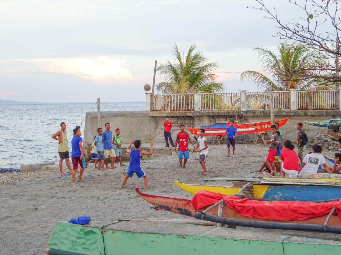 Guys playing volleyball on beach in Dumagete
