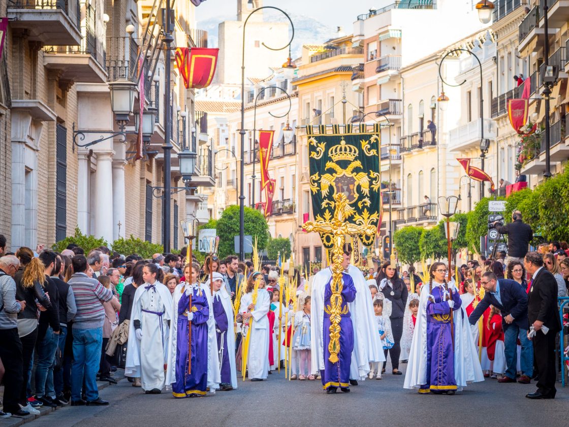 Palm Sunday procession with gold cross and banners