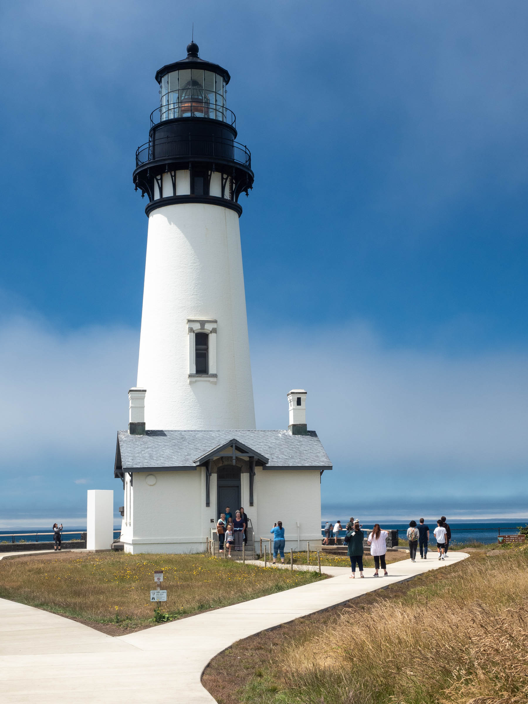 Tall white lighthouse with paths among brown grass