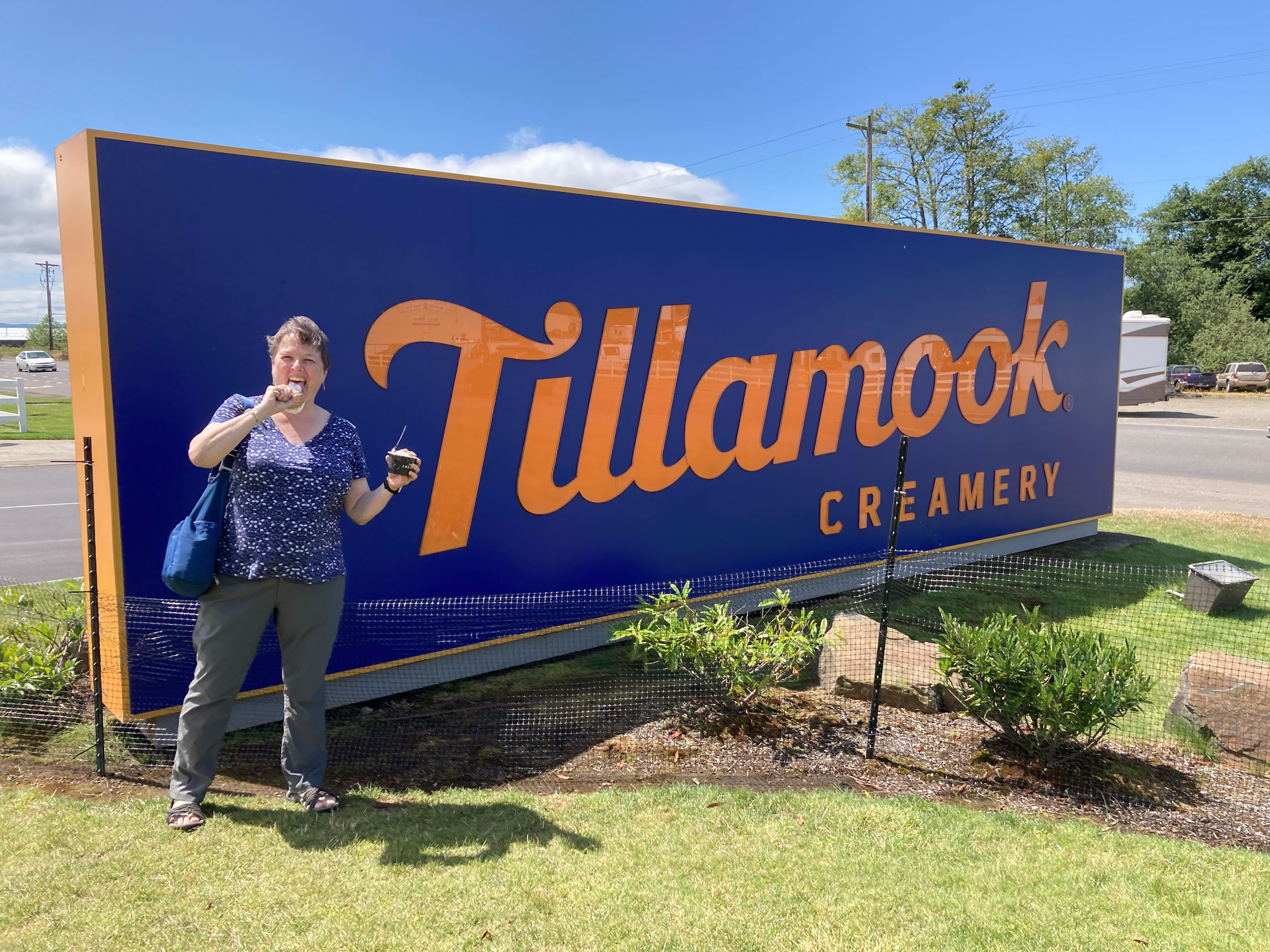 Chris holds ice cream cones by large blue sign saying Tillamook Creamery