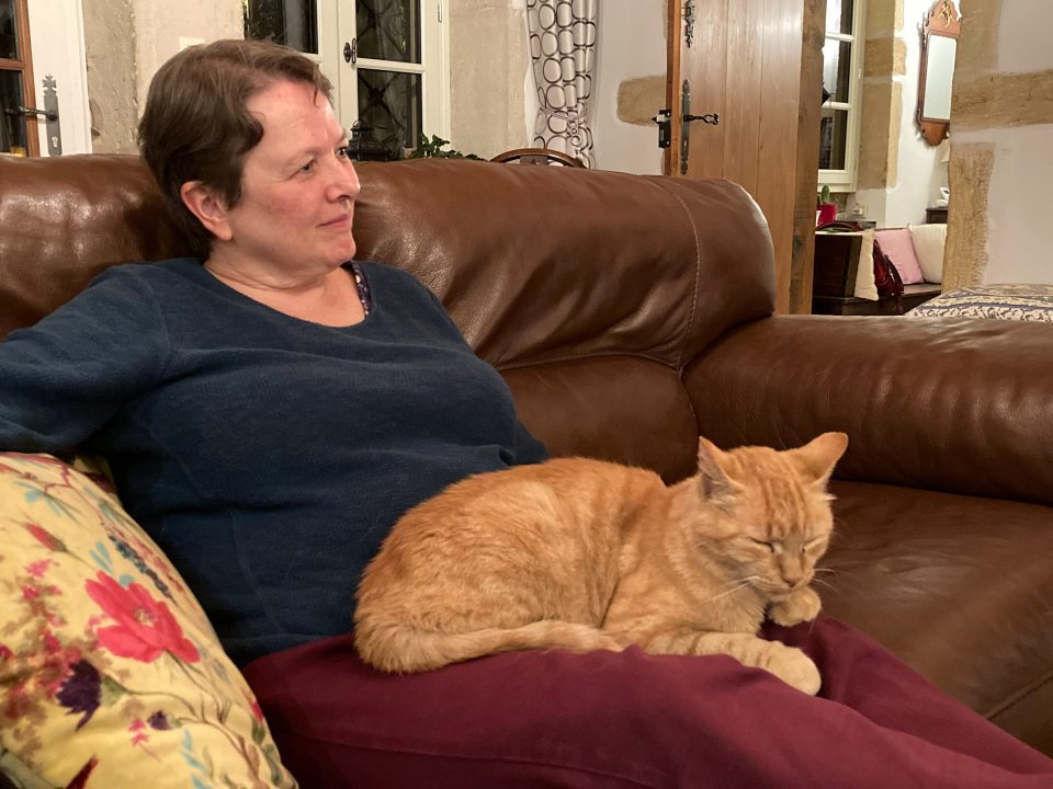 Chris on sofa with orange cat on her lap