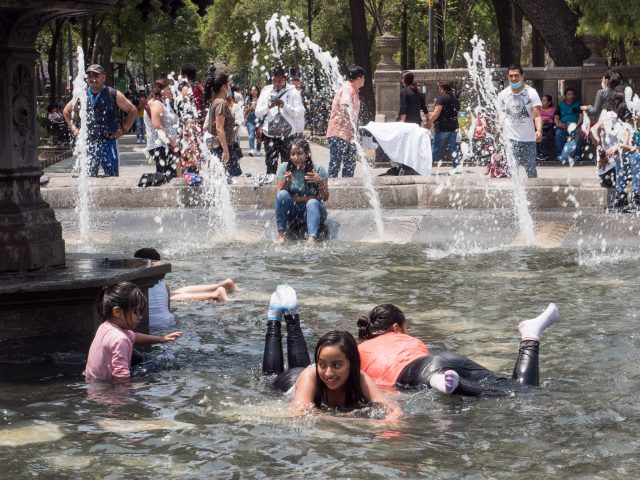 Children lying in the water in a park fountain