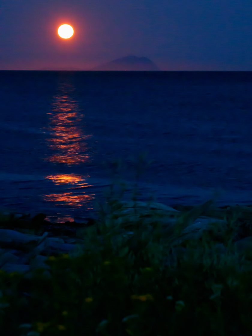 Full orange moon making orange track on the sea