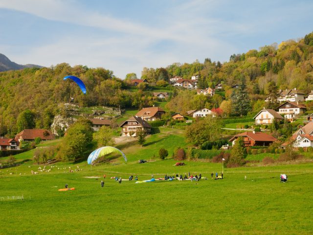 Green field with paragliders landing