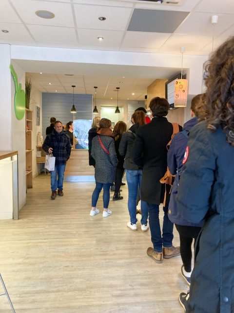 Line of people waiting to order at a carry-out salad bowl restaurant in Annecy
