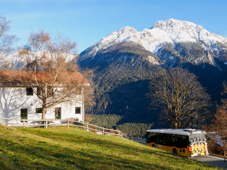 Green lawn, white house, yellow bus, and mountains in Sent
